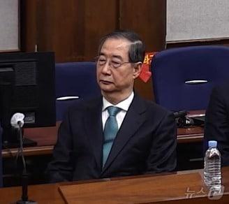 본문 이미지 - 한덕수 전 국무총리가 21일 서울 서초구 서울중앙지방법원에서 열린 내란 우두머리 방조, 내란 중요임무 종사 혐의 사건 1심 선고공판에 출석해 자리에 앉아있다. (서울중앙지방법원 제공 영상 캡쳐. 재판매 및 DB 금지) 2026.1.21/뉴스1