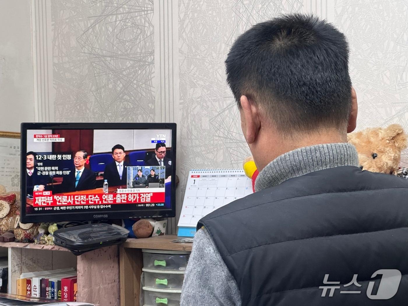 본문 이미지 - 21일 울산 중구 성남동 중앙전통시장의 한 점포에서 시민이 한덕수 전 국무총리에 대한 1심 선고 재판 TV 생중계를 보고 있다. 2026.1.21/뉴스1 ⓒ News1 김세은 기자 