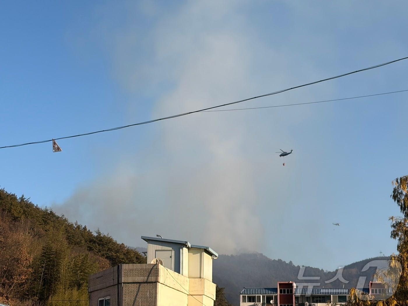 본문 이미지 - 22일 오전 9시쯤 옥곡면사무소에 마련된 임시 대피소에서 바라 본 화재현장. 21일에 비해 연기가 조금씩 잦아들고 있다. ⓒ News1 김성준 기자