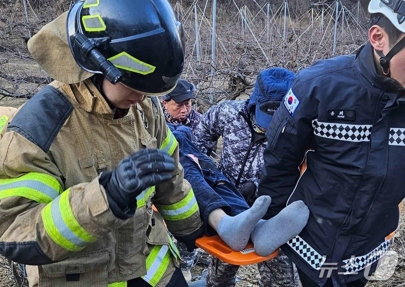본문 이미지 - 경산 와촌남성의용소방대원들이 지난 20일 소방대원과 함께 언덕에서 추락한 차량 운전자를 구조하고 있다. (경산소방서 제공. 재판매 및 DB금지)/뉴스1