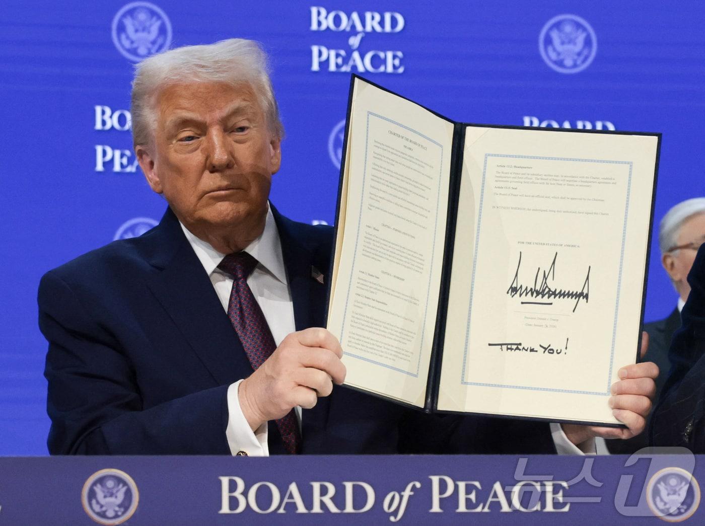 본문 이미지 - 평화위원회 헌장에 서명한 뒤 들어보이는 트럼프 미국 대통령. 2026.01.22 ⓒ 로이터=뉴스1 ⓒ News1 이지예 객원기자