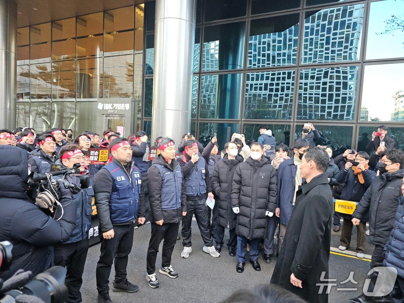 본문 이미지 - 23일 오전 서울 중구 IBK기업은행 본점에서 장민영 신임 IBK기업은행장이 첫 출근 중 노조원들의 출근 저지 투쟁에 가로막힌 채 노조원들과 대화를 하고 있다. 2026.01.23/뉴스1 ⓒ News1 정지윤 기자