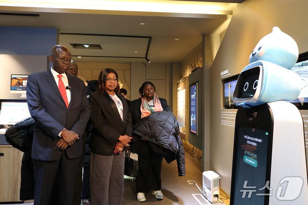 본문 이미지 - 남수단(The Republic of South Sudan) 대표단이 가뭄교육체험장에서 도슨트 로봇을 통해 가뭄 예·경보 등 가뭄 관련 종합적인 설명을 듣고 있다. 앞줄 왼쪽 첫 번째 마둣 비아 옐 남수단 고등교육·과학기술부 장관, 왼쪽 두 번째 사라 클레토 리알 남수단 보건부 장관. (한국수자원공사 제공.재판매 및 DB 금지)/뉴스1