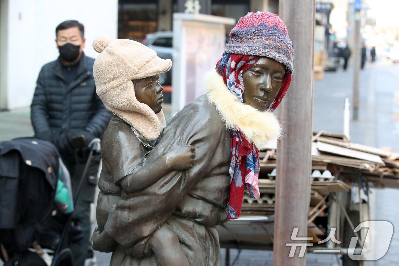 본문 이미지 - 동장군이 기승을 부린 23일 오후 대구 중구 종로 약령시 인근에 세워진 '엄마의 마음' 조각상(이현우 작)에 시민들이 씌워놓은 방한모와 목도리가 눈길을 끌고 있다. 이 조각은 김원일의 소설 '마당 깊은 집' 주인공 길남엄마가 막내 길수를 업고 신문 배달 나간 길남이를 기다리는 모습을 형상화한 작품이다. 2026.1.23/뉴스1 ⓒ News1 공정식 기자