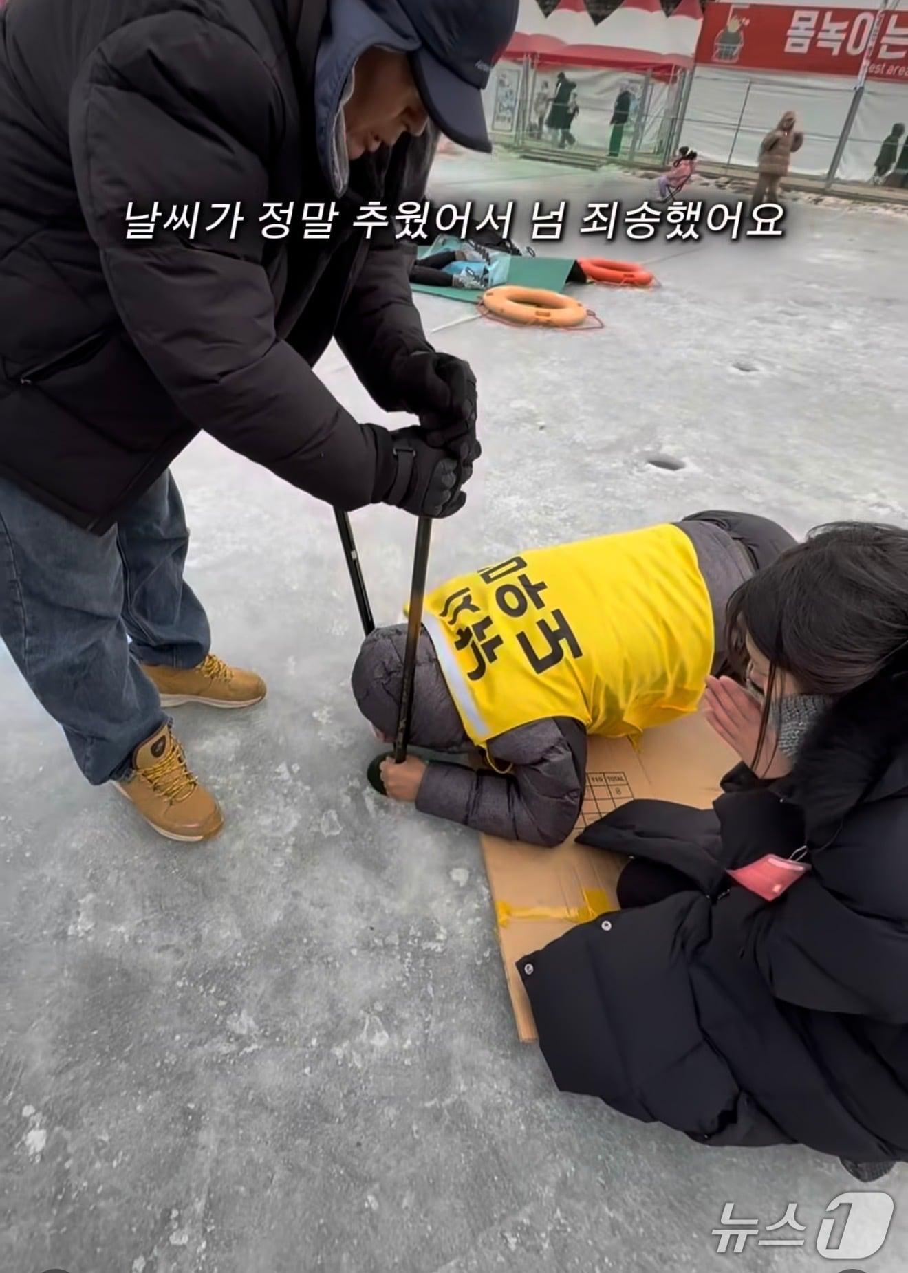 본문 이미지 - 관광객이 화천 산천어를 잡고 기뻐하다 낚시 구멍에 휴대폰을 빠뜨린 가운데 '낚시 도우미'가 휴대폰을 건지기 위해 노력을 하고 있다.(A 씨 SNS 캡처, 재판매 및 DB금지)