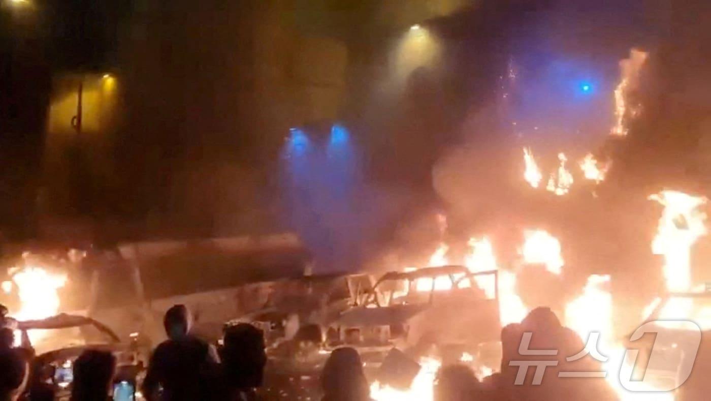 본문 이미지 - 이란에서 반정부 시위가 한창이던 지난 9일 테헤란의 시위대 옆으로 불타는 차량의 모습이 보인다. 2026.1.9 ⓒ 로이터=뉴스1 ⓒ News1 강민경 기자