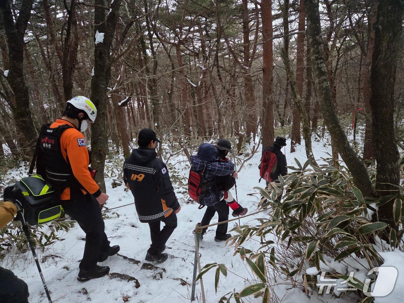 본문 이미지 - 지난 25일 오후 제주 한라산에서 낙상 사고로 다친 등반객이 소방대원에게 업혀 하산하고 있다.(제주도소방안전본부 제공. 재판매 및 DB 금지)