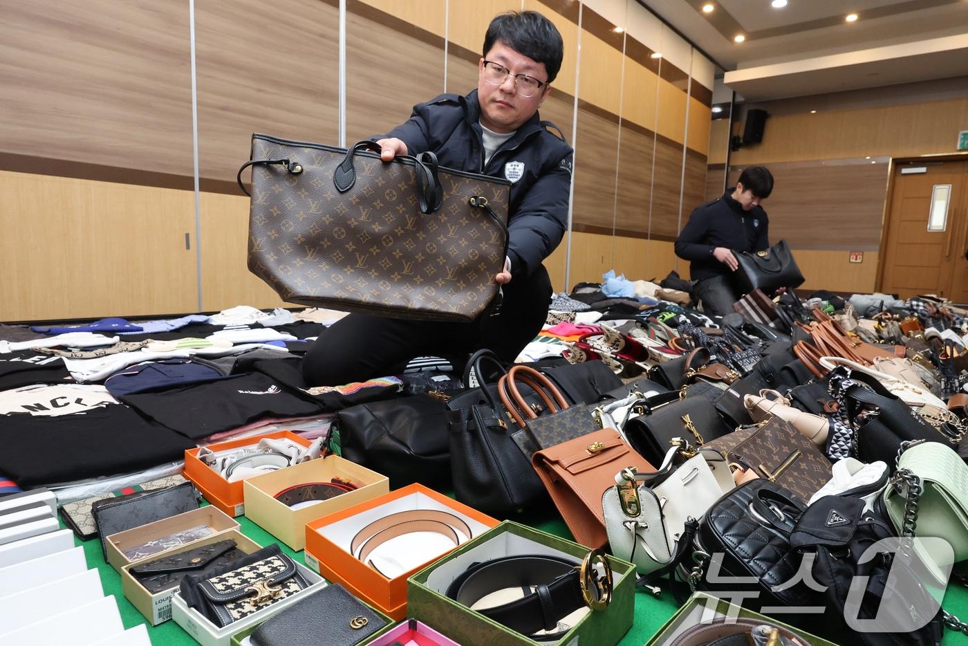 본문 이미지 - 27일 오전 인천 중구 인천본부세관에서 열린 '1200억원대 위조 명품 판매 쇼핑몰 운영조직 적발' 브리핑에서 직원들이 압수품을 살펴보고 있다. 관세청 인천본부세관은 이날 관세법·상표법·범죄수익은닉규제법 위반 등의 혐의로 온라인 쇼핑몰 소유자 40대 A 씨를 검찰에 구속 송치했다고 밝혔다. 2026.1.27/뉴스1 ⓒ News1 황기선 기자