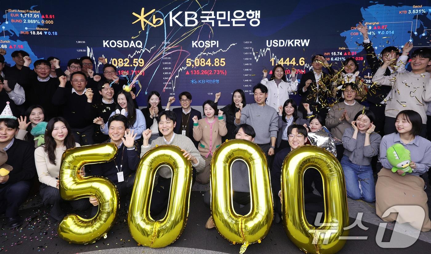 본문 이미지 - 코스피가 종가 기준 사상 처음 5000선을 돌파한 27일 오후 서울 영등포구 KB국민은행 딜링룸에서 직원들이 축하 세리머니를 하고 있다. 이날 코스피지수는 전일대비 135.26p(2.73%) 오른 5084.85로 장을 마감했다. 2026.1.27/뉴스1 ⓒ News1 박지혜 기자
