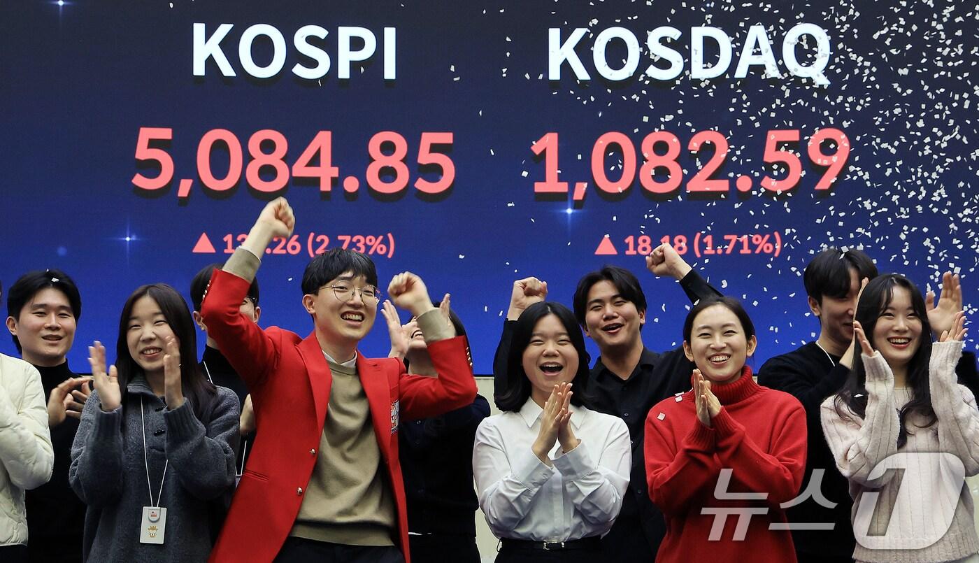 본문 이미지 - 한국 증시 최초로 종가 기준 코스피 5000을 달성한 27일 서울 영등포구 한국거래소에서 직원들이 코스피 종가가 표시된 전광판을 배경으로 세레머니를 하고 있다. 2026.1.27/뉴스1 ⓒ News1 이호윤 기자