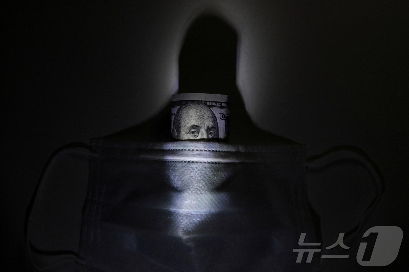 본문 이미지 - 보호용 마스크 뒤에 배치된 미국 달러 지폐를 묘사한 일러스트레이션 ⓒ 로이터=뉴스1