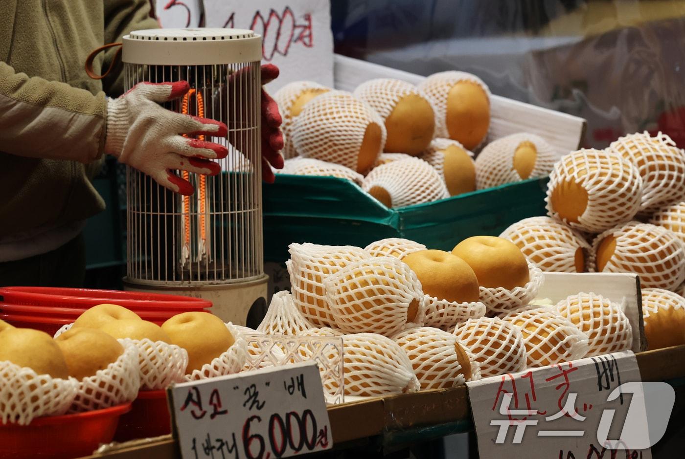 본문 이미지 -  28일 오전 서울 동대문구의 한 전통시장에서 과일가게 상인이 언 손을 녹이고 있다. 2026.1.28/뉴스1 ⓒ News1 오대일 기자