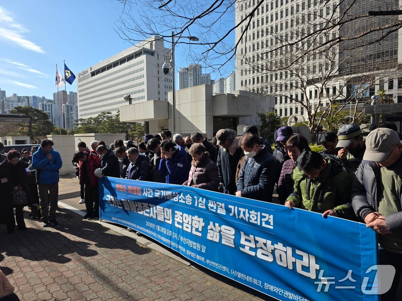 본문 이미지 - 28일 부산지방법원 정문 앞에서 영화숙·재생원 피해자들이 이미 세상을 떠난 피해자들에 대해 묵념하고 있다.2026.1.28/뉴스1 ⓒNews1 장광일 기자