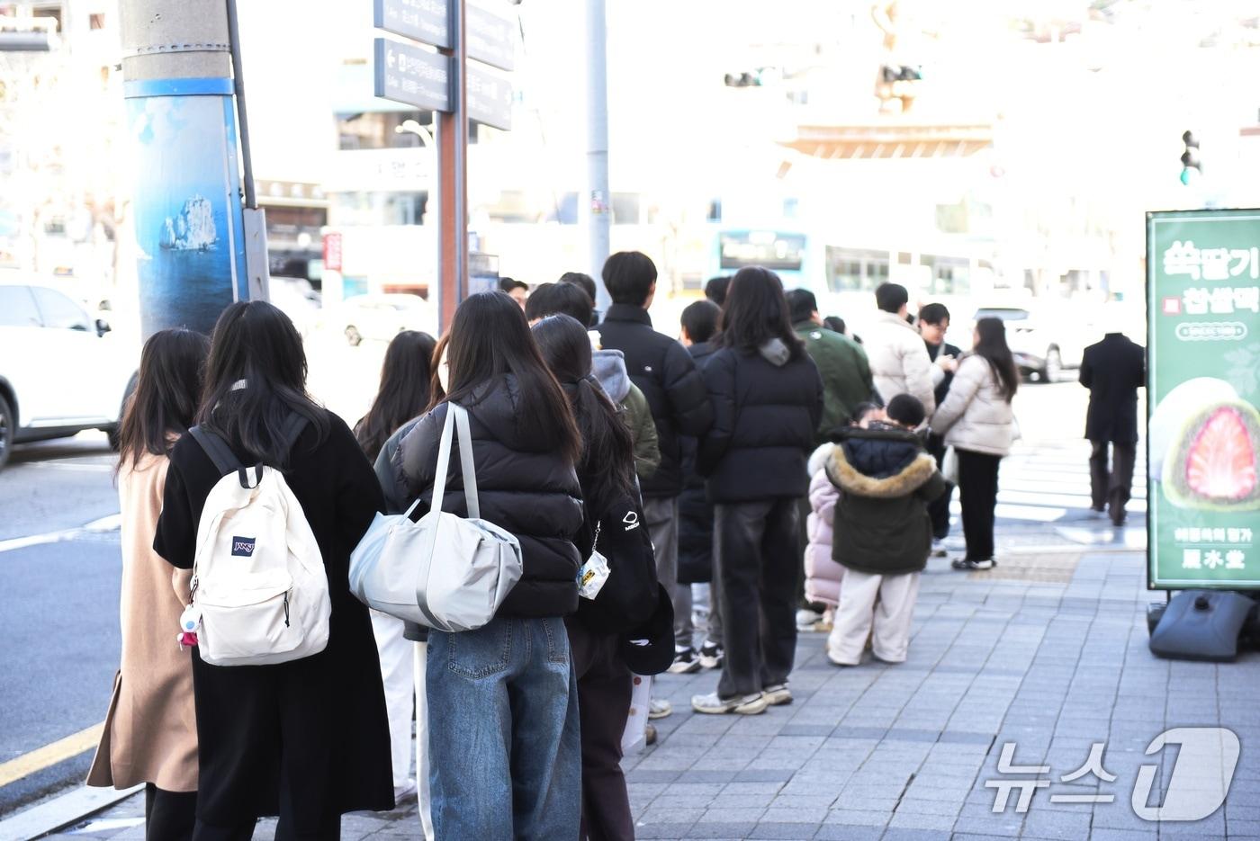 본문 이미지 - 31일 추위가 누그러진 가운데 전남 여수를 방문한 관광객들이 한 상점앞에 줄을 서 있다. 뉴스1