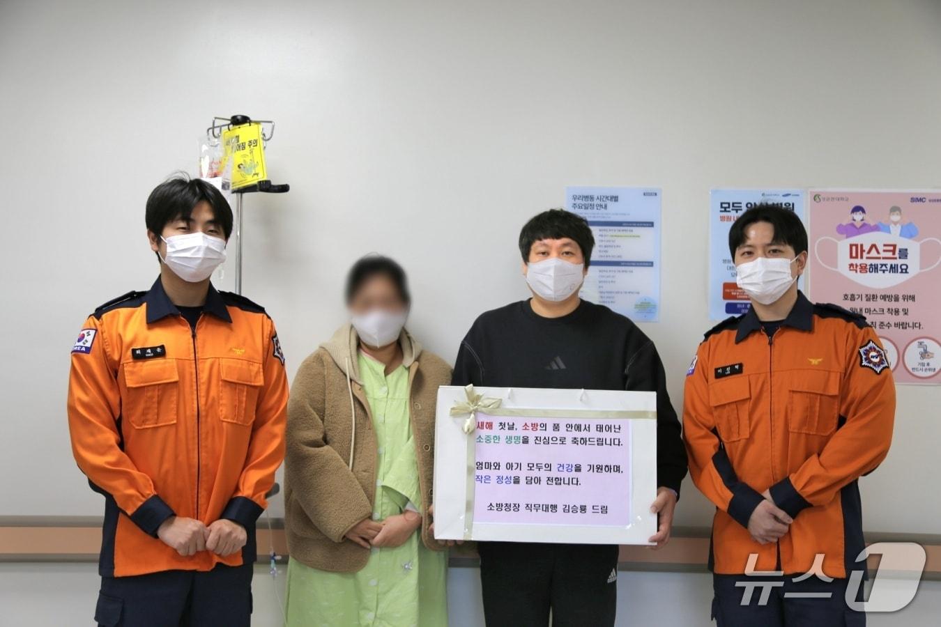 본문 이미지 - 소방헬기 안에서 태어난 새 생명에게 소방공무원들의 마음을 담아 '새해 첫 특별선물'을 전달하고 있다.(소방청 제공)