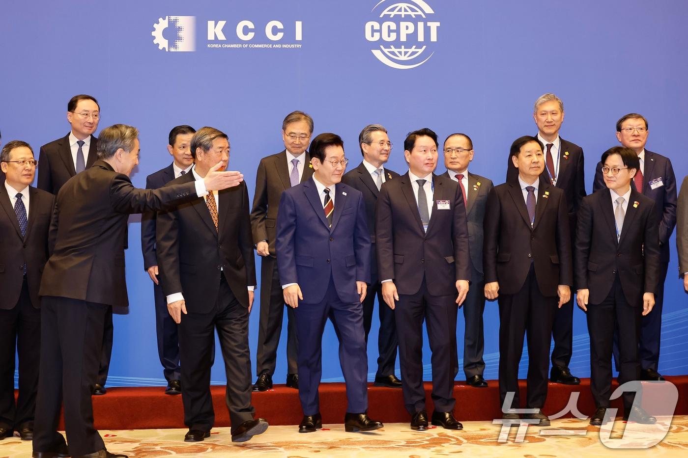 본문 이미지 - 이재명 대통령이 5일 중국 베이징 조어대에서 열린 한중 비즈니스포럼에서 참석자들과 기념촬영을 마친 뒤 이동하고 있다. 이 대통령 오른쪽은 최태원 대한상공회의소 회장. 2026.1.5 ⓒ 뉴스1 허경 기자