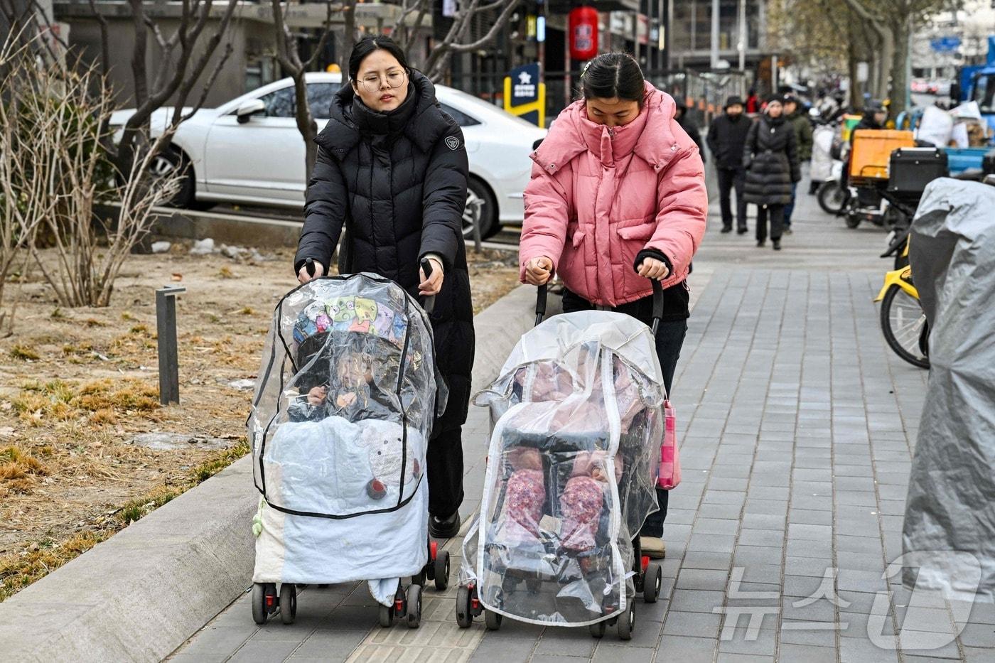 4일 중국 베이징의 한 길거리에서 한 여성들이 아이를 태운 유모차를 끌면서 이동하고 있다. 2026.01.04 ⓒ AFP=뉴스1 ⓒ News1 김지완 기자
