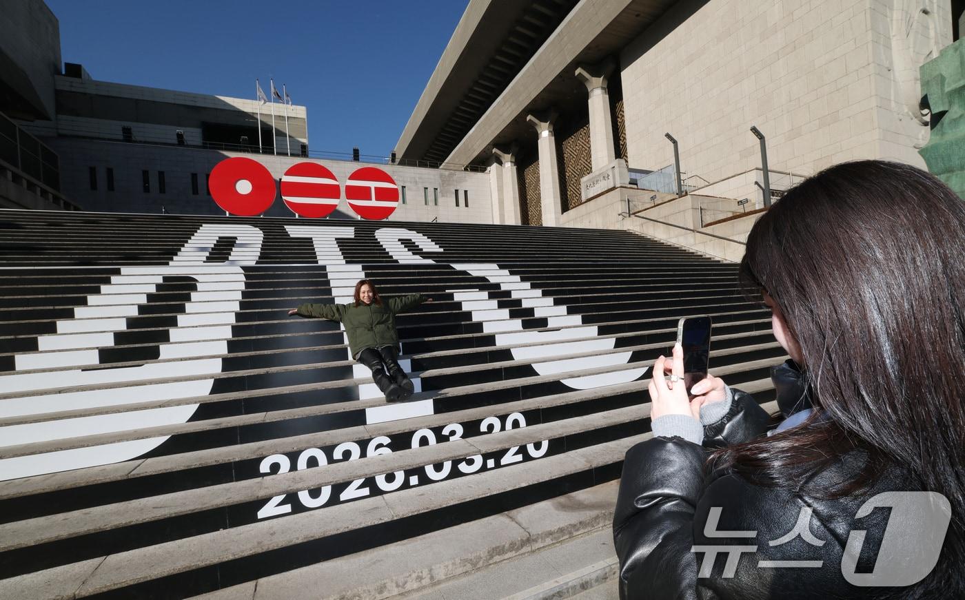 본문 이미지 - 6일 오전 서울 종로구 세종문화회관 야외 계단에 설치된 BTS(방탄소년단)의 컴백 로고 조형물 앞에서 관광객들이 기념촬영을 하고 있다. BTS는 3월 20일 컴백과 새 앨범 발매, 월드투어 일정을 공식 발표했다. 2026.1.6/뉴스1 ⓒ News1 임세영 기자
