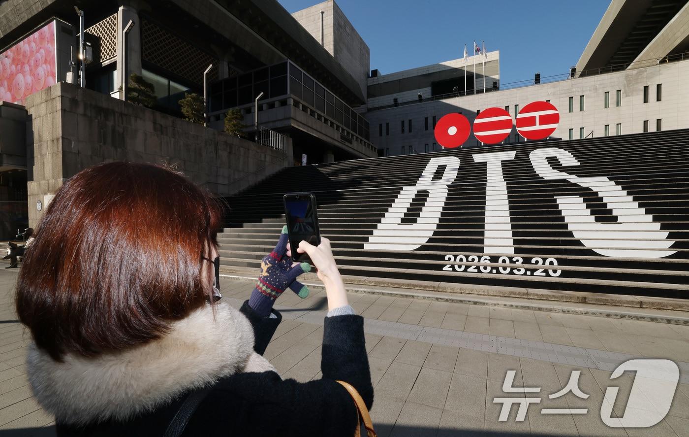 본문 이미지 - 6일 오전 서울 종로구 세종문화회관 야외 계단에 설치된 BTS(방탄소년단)의 컴백 로고 조형물 앞에서 관광객이 기념촬영을 하고 있다. BTS는 3월 20일 컴백과 새 앨범 발매, 월드투어 일정을 공식 발표했다. 2026.1.6/뉴스1 ⓒ News1 임세영 기자