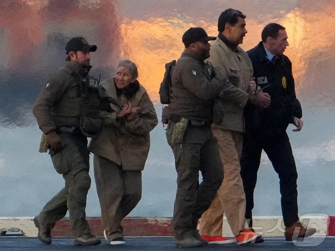 본문 이미지 - 미국 마약단속국(DEA) 요원들이 체포된 니콜라스 마두로 베네수엘라 대통령과 부인 실리아 플로레스를 헬리콥터에서 내리게 하고 있다. 2026.01.05. ⓒ 로이터=뉴스1 ⓒ News1 이정환 기자