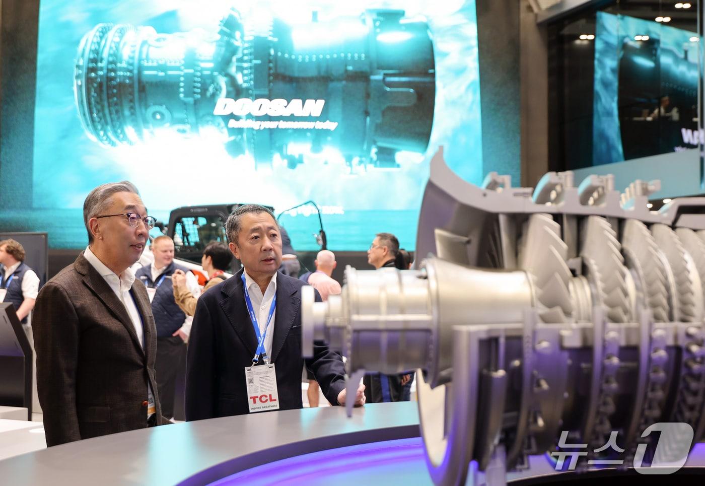 본문 이미지 -  박정원(오른쪽) 두산그룹 회장과 박지원 그룹부회장이 7일(현지시간) 미국 라스베이거스에서 열리고 있는 CES 2026 현장에서 두산 부스에 전시된 가스터빈 모형을 살펴보고 있다. (사진제공 = 두산)