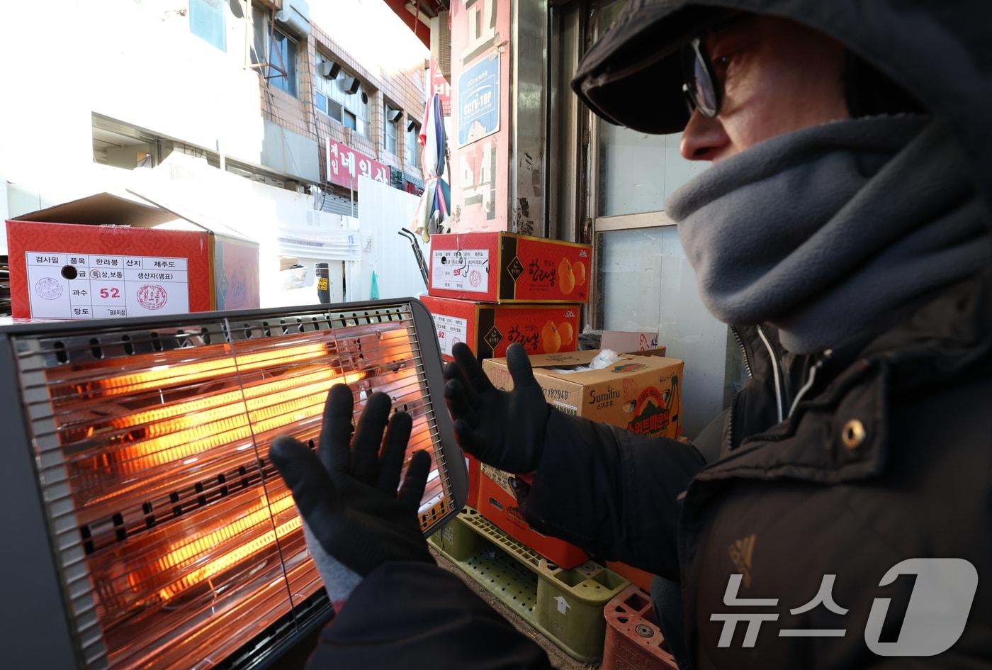 전국 대부분 지역에 영하권 추위를 보인 8일 경기 수원시 팔달구 영동시장에서 상인들이 전기난로에 몸을 녹이고 있다. 2026.1.8/뉴스1 ⓒ News1 김영운 기자