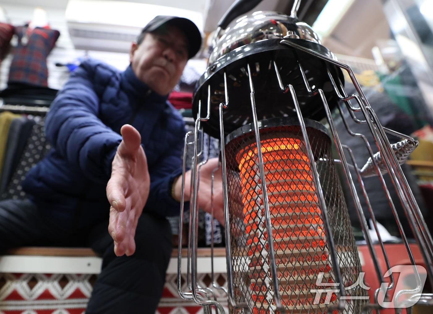 본문 이미지 - 전국 대부분 지역에 영하권 추위를 보인 8일 경기 수원시 팔달구 영동시장에서 상인들이 전기난로에 몸을 녹이고 있다. 2026.1.8/뉴스1 ⓒ News1 김영운 기자