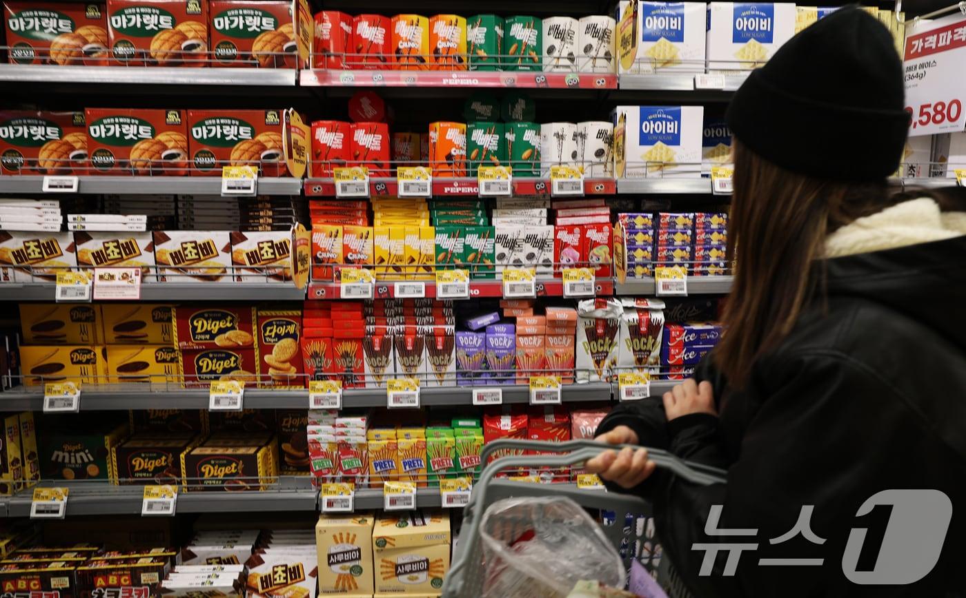 본문 이미지 - 고환율과 이상기후, 원재료 가격 상승으로 새해 '식탁 물가'에 비상이 걸렸다. 가공식품·외식·농수산물 등이 먹거리 물가 상승을 주도하고 있다. 사진은 8일 서울시내의 한 대형마트에서 고객이 과자를 고르는 모습. 2026.1.8 ⓒ 뉴스1 오대일 기자