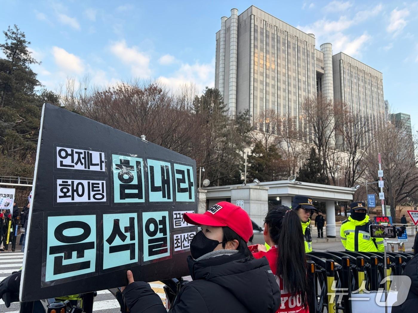 본문 이미지 - 윤 전 대통령 지지자들 50여 명은 이날 오전 8시 30분쯤부터 서울 서초구 서울중앙지법 서문 인근에 모여 윤 전 대통령에 대한 수사와 재판이 부당하다며 "불법 구속 즉각 석방", "윤 어게인(Yoon Again)" 등 구호를 외쳤다. 2026.1.9/ 뉴스1 김종훈