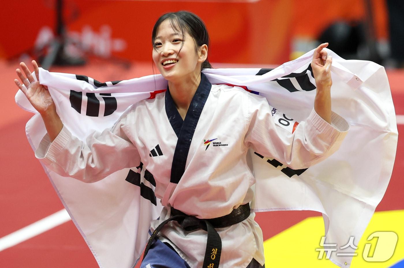 본문 이미지 - 대한민국 정하은이 1일 일본 도요하시 체육관에서 열린 2026 아이치·나고야 아시안게임 태권도 여자 개인 품새 결승전에서 금메달을 확정 짓자 태극기를 둘러멘채 기뻐하고 있다. 2026.10.1 ⓒ 뉴스1 안은나 기자