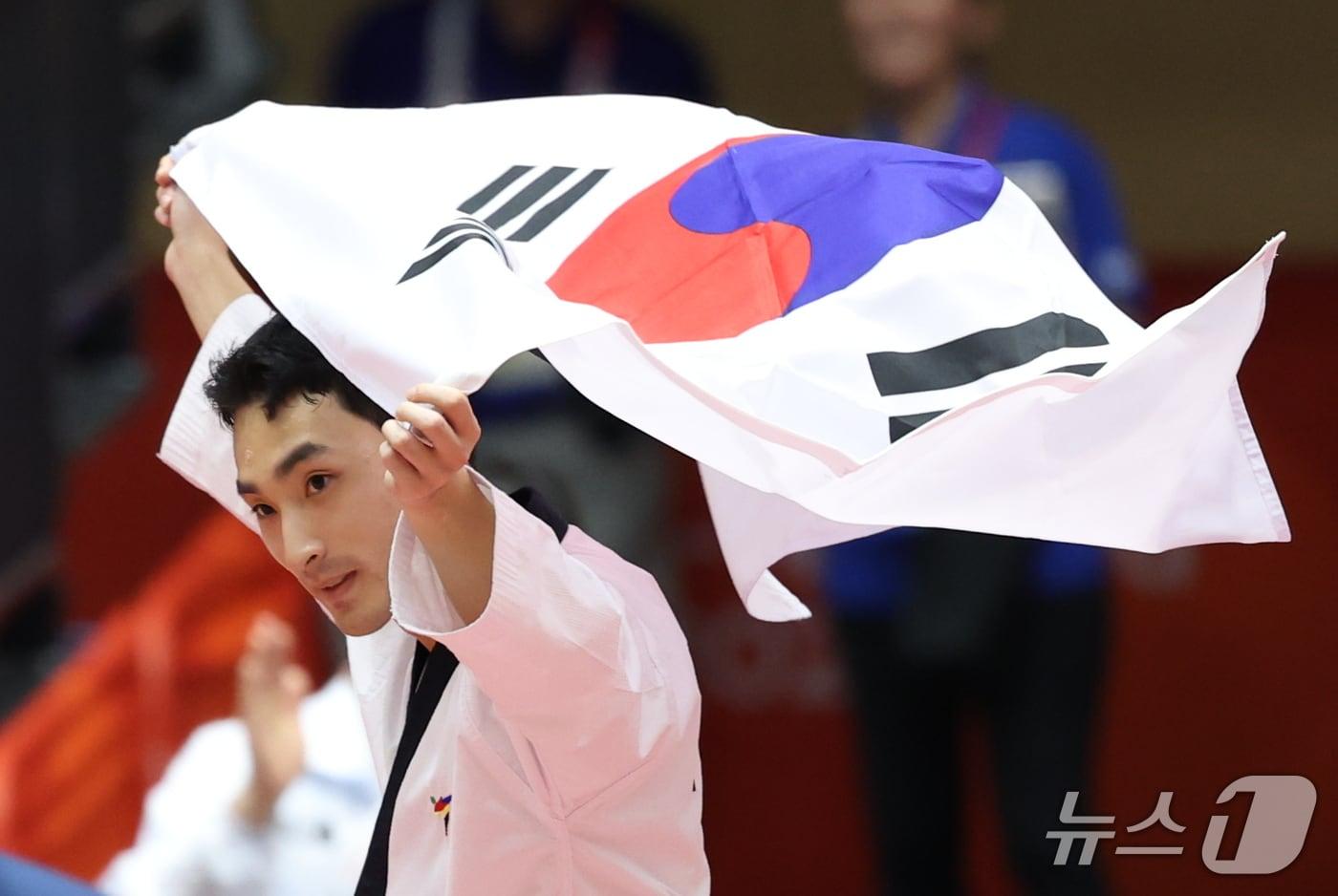본문 이미지 - 대한민국 윤규성이 1일 일본 도요하시 체육관에서 열린 2026 아이치·나고야 아시안게임 태권도 남자 개인 품새 결승전에서 금메달을 획득한 후 태극기를 펼쳐 들며 기뻐하고 있다. 2026.10.1 ⓒ 뉴스1 안은나 기자
