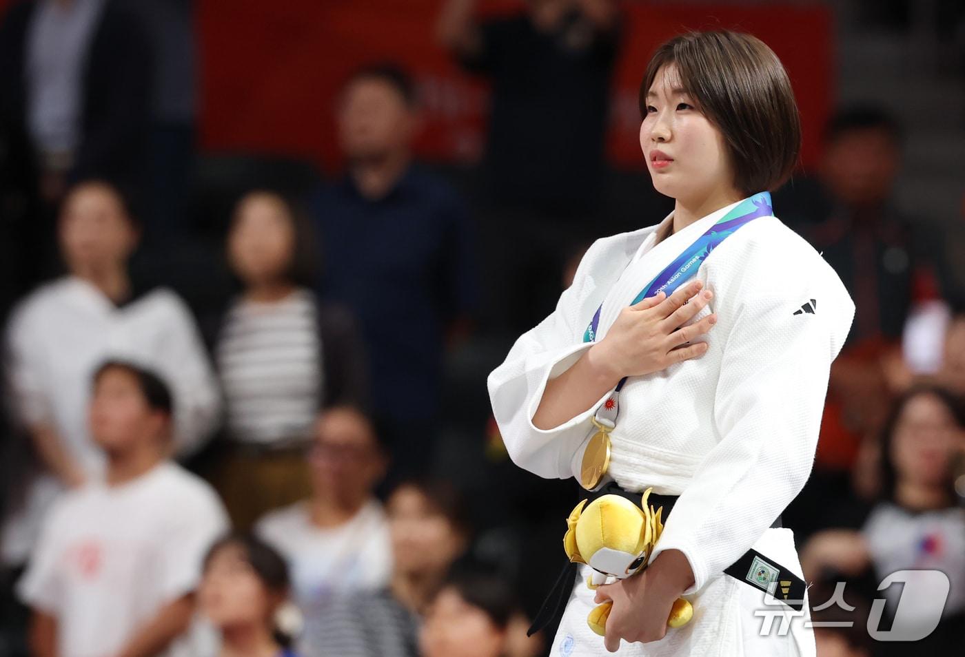 본문 이미지 - 대한민국 허미미가 1일 일본 아이치 인터내셔널 아레나에서 열린 2026 아이치·나고야 아시안게임 유도 여자 57kg급 결승 시상식에서 금메달을 목에 걸고 국민의례를 하고 있다. 2026.10.1 ⓒ 뉴스1 김민지 기자