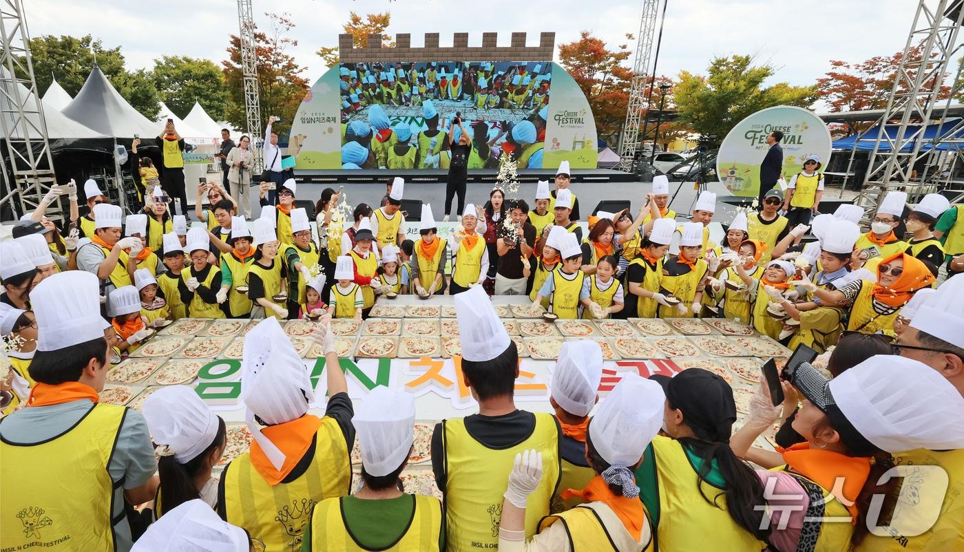 본문 이미지 - 11일 전북 임실군 임실치즈테마파크에서 열린 2026 임실N치즈축제에서 한득수 군수와 정일윤 군의장이 대형쌀피자 만들기에 참여해 관광객들과 치즈를 뿌리는 퍼포먼스를 하고 있다. (임실군 제공. 재판매 및 DB 금지) 2026.10.11 ⓒ 뉴스1