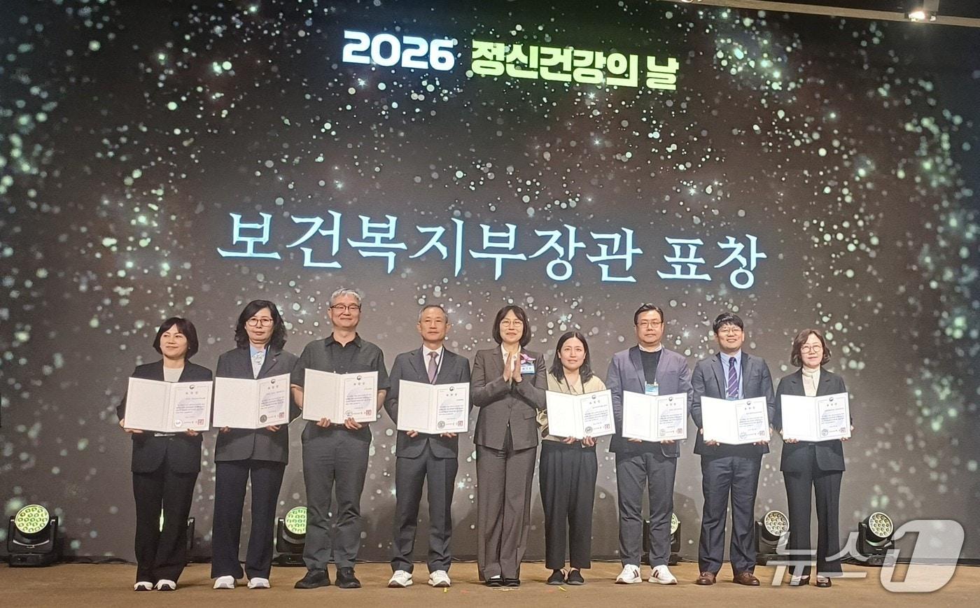 본문 이미지 -  경기 군포시 관계자들이 8일 서울 용산구 피스앤파크 컨벤션에서 열린 '2026년 세계 정신건강의 날 기념식'에서 복지부 장관 표창을 수상한 후 기념촬영을 하고 있다. (군포시 제공. 재판매 및 DB 금지) 2026.10.12/뉴스1
