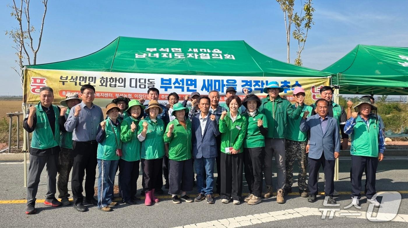 본문 이미지 - 부석면새마을지회와 부녀회 및 지역 사회단체가 경작지 추수 행사 기념촬영을 하고 있다.ⓒ 뉴스1 김태완 기자