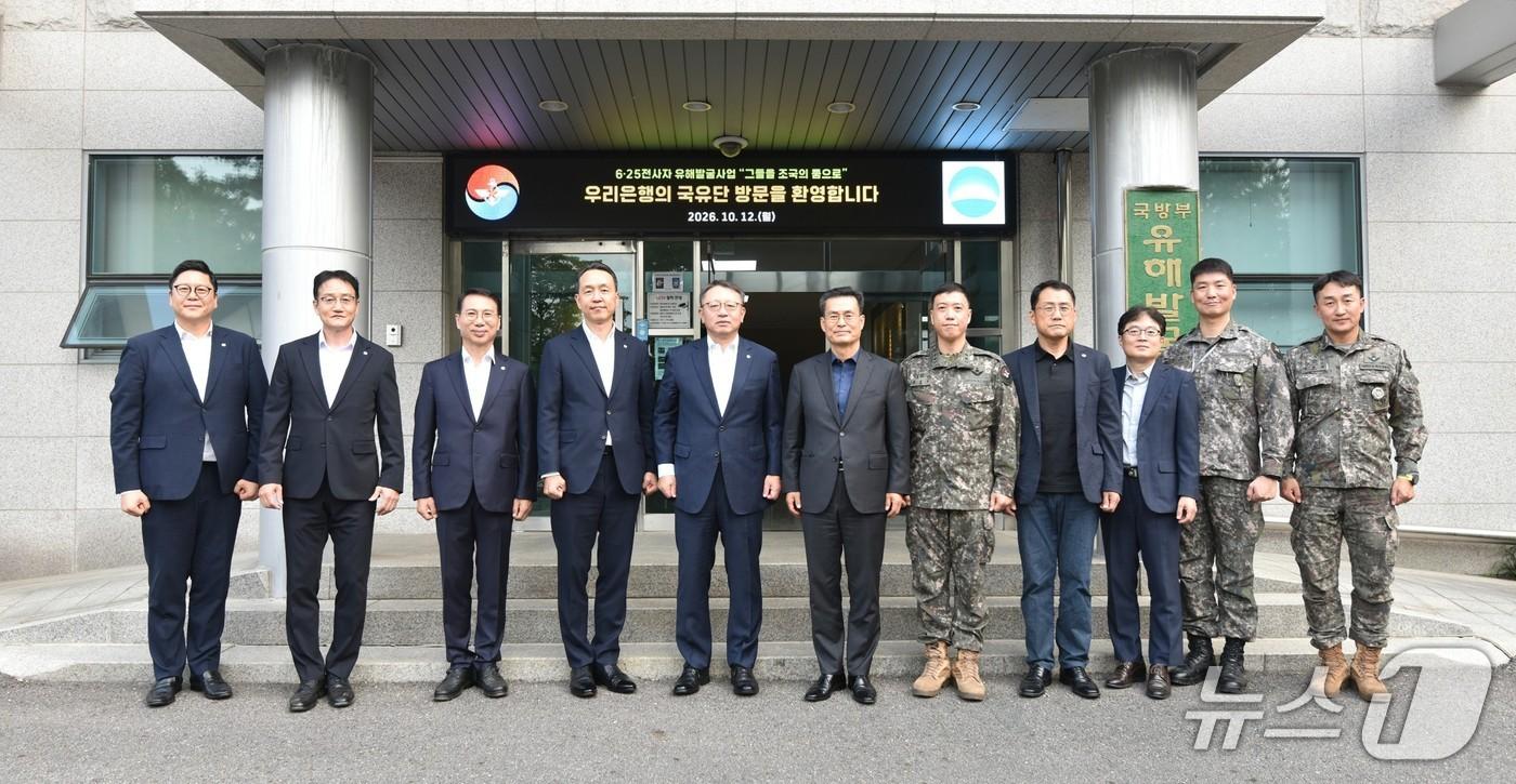 본문 이미지 - 지난 12일 국립서울현충원 내 국방부 유해발굴감식단에서 (왼쪽 다섯 번째부터) 정진완 우리은행장, 전병희 국방부 유해발굴감식단장과 양 기관 주요 관계자들이 기념사진을 촬영하고 있다. 2026.10.12 / 사진제공=우리은행