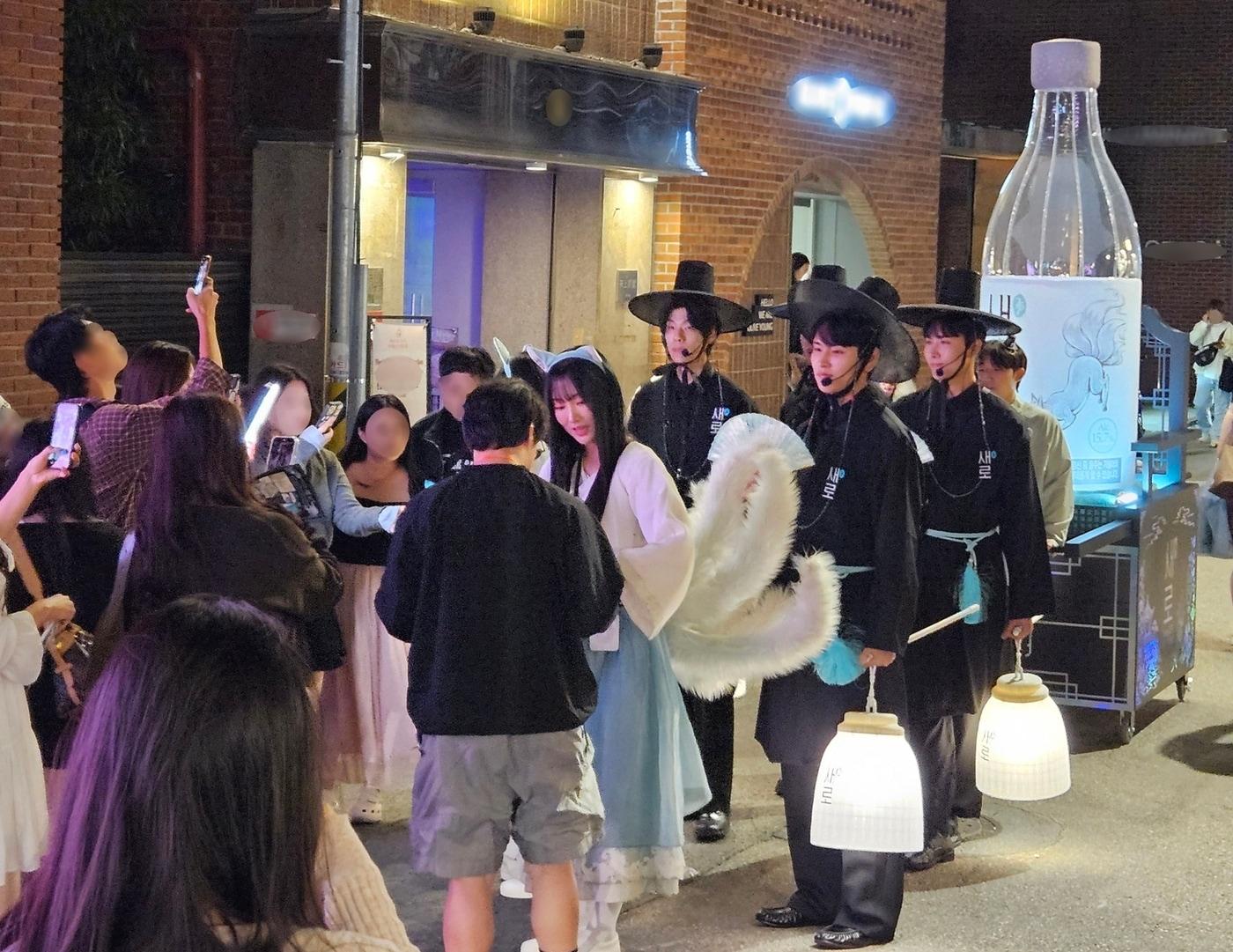 본문 이미지 - 서울 시내 주요 상권에서 '새로구미'와 '저승사자'로 분장한 새로 행사팀이 거리를 행진하며 소비자들에게 새로의 신규 광고를 소개한 웹툰 형태의 전단과 구강 청결제를 나눠주고 있다.(롯데칠성음료 제공)