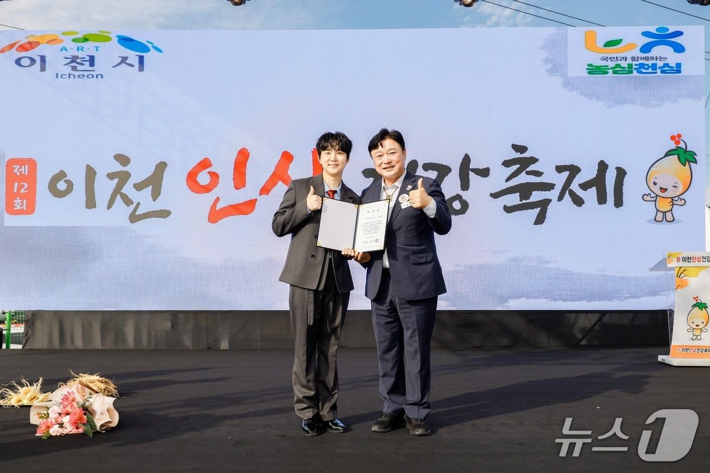 본문 이미지 - 성수석 시장(오른쪽)이 가수 추혁진에게 홍보대사 위촉장을 전달한 뒤 기념촬영을 하고 있는 모습.(이천시 제공)