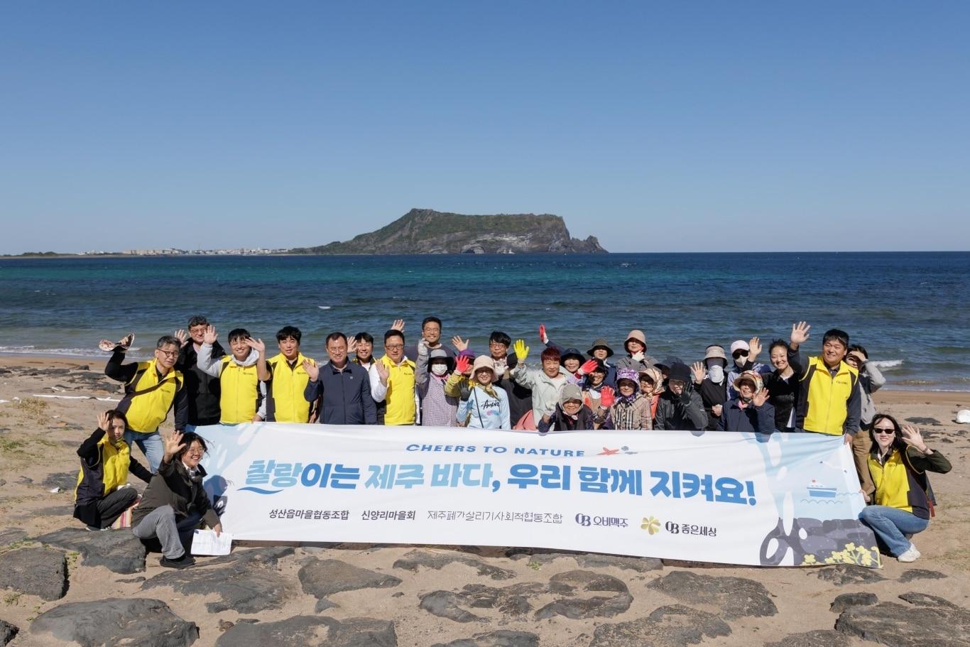 본문 이미지 - 오비맥주 임직원들이 10월 14일 제주 서귀포시 섭지코지 일대에서 지역 주민들과 함께 해변 정화 활동을 펼친 뒤 기념사진을 촬영하고 있다.(오비맥주 제공)