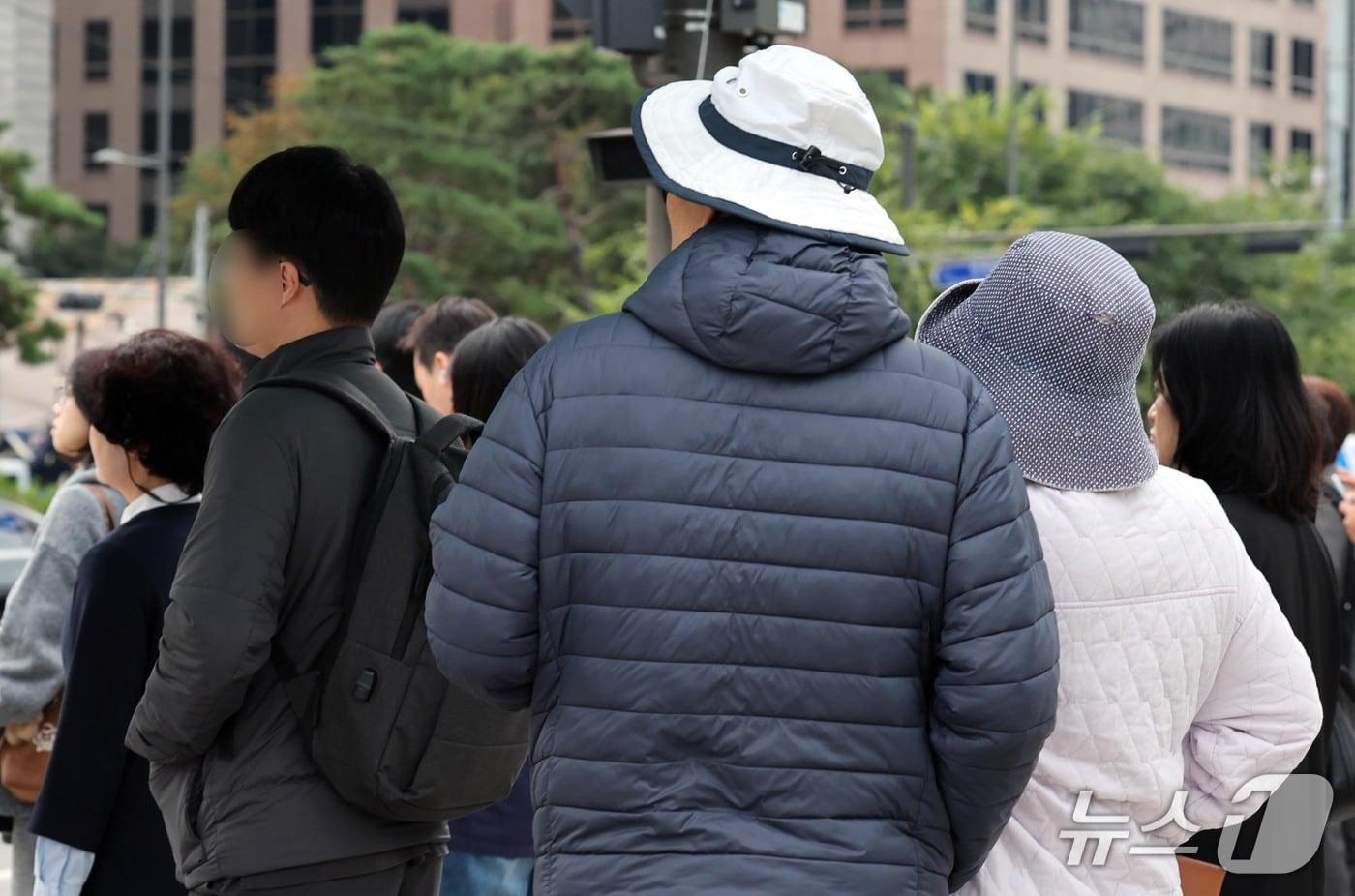 본문 이미지 - 19일 가을비 내린 뒤 '쌀쌀한 출근길'에 서울 세종로에서 시민들이 두꺼운 외투차림으로 보행신호를 기다리고 있다. 2026.10.19 ⓒ 뉴스1 이종덕 기자