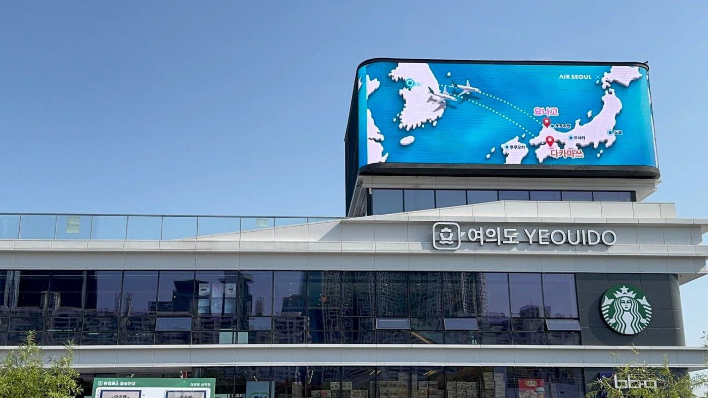 본문 이미지 - 서울 영등포구 여의도동 소재 한강버스 선착장에 에어서울 취항지 일본 다카마쓰와 요나고를 소개하는 옥외 광고 영상이 상영되는 모습.(에어서울 제공). 2026.10.19.