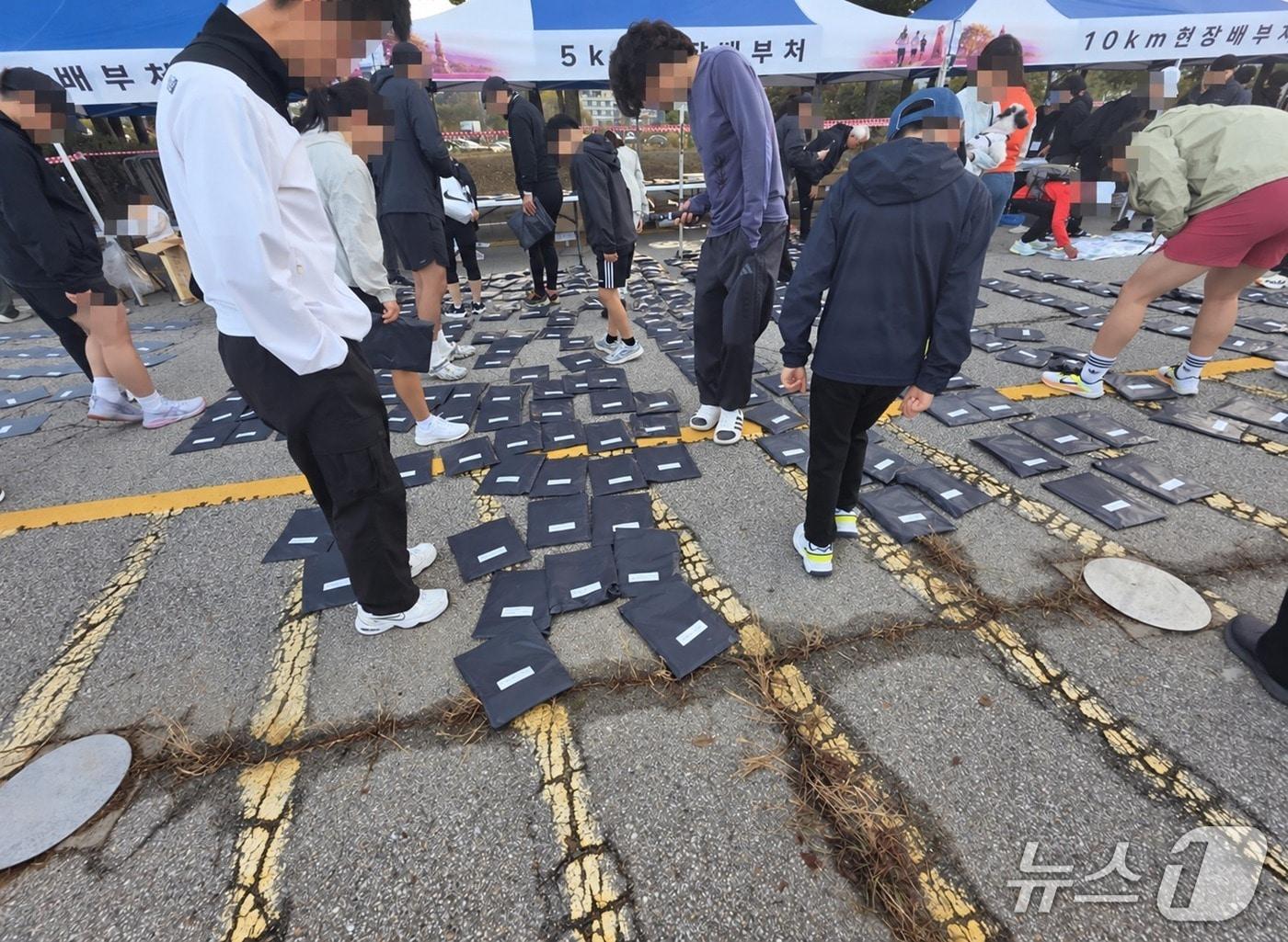 본문 이미지 - 지난 5일 열린 '2026 양주 천일홍 마라톤대회' 현장에 참가자들의 배번호와 기념품 등이 담긴 봉투가 바닥에 펼쳐져 있다. 참가자들은 직접 자신의 배번호를 찾아야 했다. (독자제공 사진)
