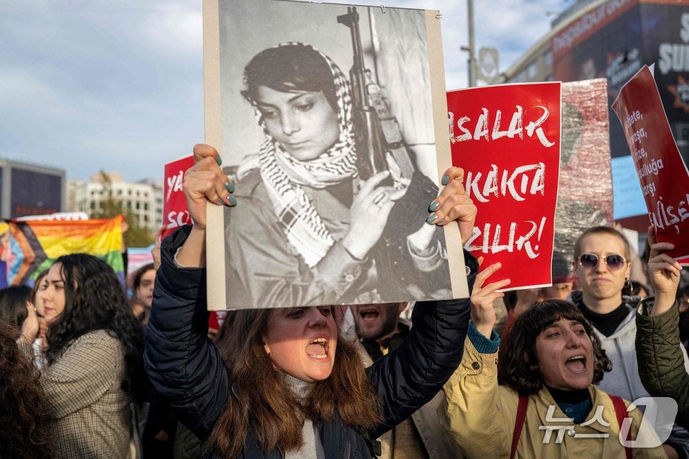 본문 이미지 - 무장 단체 팔레스타인 해방 인민전선(PFLP)의 라일라 칼레드 초상화를 들고 있는 튀르키예 여성. 2023.11.25 ⓒ AFP=뉴스1