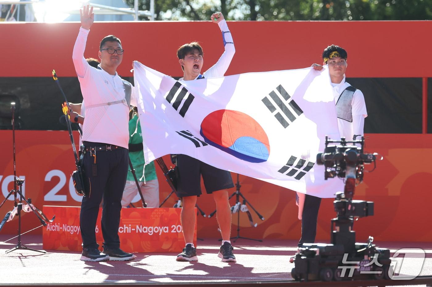 본문 이미지 - 대한민국 김우진 이우석 김제덕이 2일 일본 오카자키 중앙종합공원 다목적광장에서 열린 2026 아이치·나고야 아시안게임 양궁 리커브 남자 단체전 결승 대한민국과 인도의 경기에서 금메달을 확정 지은 후 태극기를 들고 기뻐하고 있다. 2026.10.2 ⓒ 뉴스1 김민지 기자