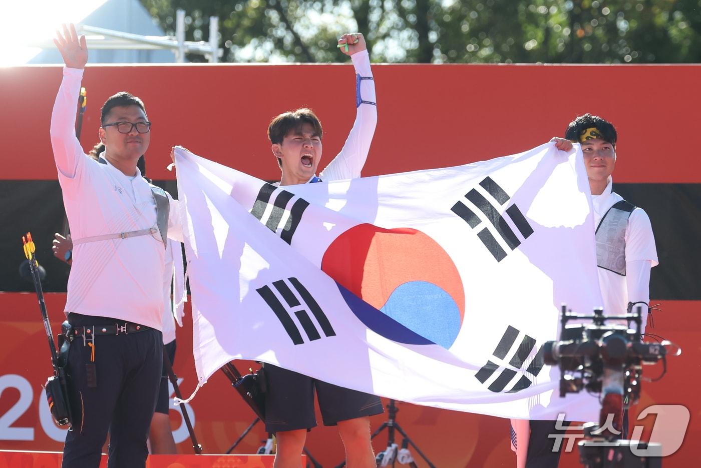 본문 이미지 - 대한민국 김우진 이우석 김제덕이 2일 일본 오카자키 중앙종합공원 다목적광장에서 열린 2026 아이치·나고야 아시안게임 양궁 리커브 남자 단체전 결승 대한민국과 인도의 경기에서 금메달을 확정 지은 후 태극기를 들고 기뻐하고 있다. 2026.10.2 ⓒ 뉴스1 김민지 기자