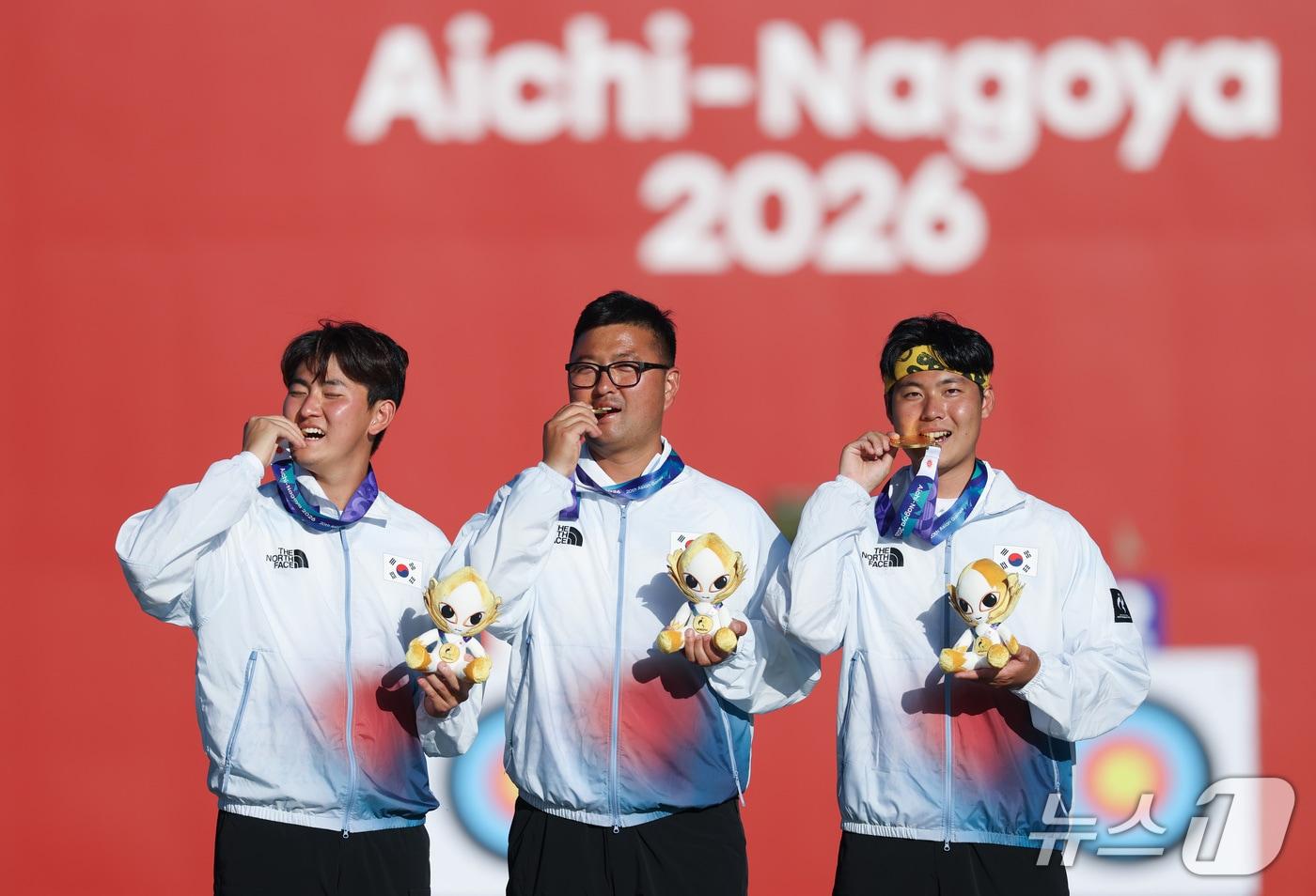 본문 이미지 - 대한민국 김제덕(왼쪽부터), 김우진, 이우석이 2일 일본 오카자키 중앙종합공원 다목적광장에서 열린 2026 아이치·나고야 아시안게임 양궁 리커브 남자 단체전 결승 시상식에서 금메달을 깨물고 있다. 2026.10.2 ⓒ 뉴스1 김민지 기자