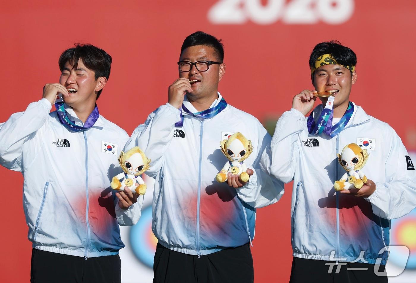 본문 이미지 - 대한민국 김제덕(왼쪽부터), 김우진, 이우석이 2일 일본 오카자키 중앙종합공원 다목적광장에서 열린 2026 아이치·나고야 아시안게임 양궁 리커브 남자 단체전 결승 시상식에서 금메달을 깨물고 있다. 2026.10.2 ⓒ 뉴스1 김민지 기자
