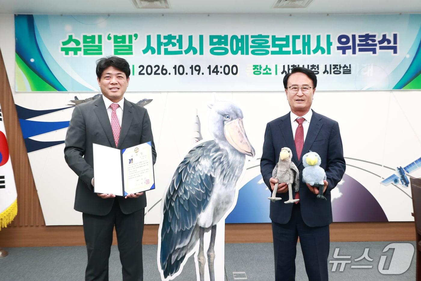 본문 이미지 - 박동식 사천시장(오른쪽)이 19일 시청 시장실에서 슈빌 '빌'의 명예홍보대사 위촉장을 김승민 아라마루 아쿠아리움 대표에게 전달하고 있다(사천시 제공. 재판매 및 DB 금지).