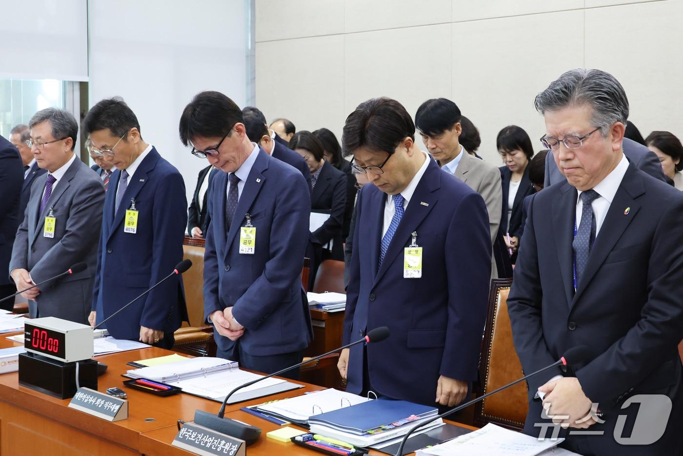 본문 이미지 - 고상백 한국보건산업진흥원장을 비롯한 국정감사 증인이 20일 서울 여의도 국회에서 열린 보건복지위원회의 한국보건산업진흥원 등에 대한 국정감사에서 부천 공장 화재 현장에서 순직한 고(故) 김진석 소방위를 추모하고 있다.  ⓒ 뉴스1 신웅수 기자