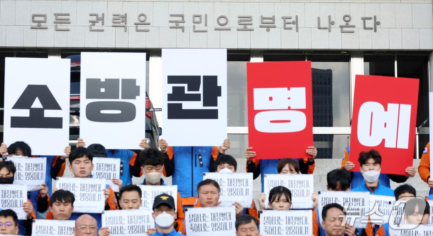 본문 이미지 - 21일 서울 영등포구 여의도 국회의사당 계단에서 대한민국공무원노동조합총연맹 소방공무원노동조합원들이 소방공무원 명예회복과 소방조직 정상화 촉구 기자회견을 하고 있다. 2026.10.21 ⓒ 뉴스1 김명섭 기자